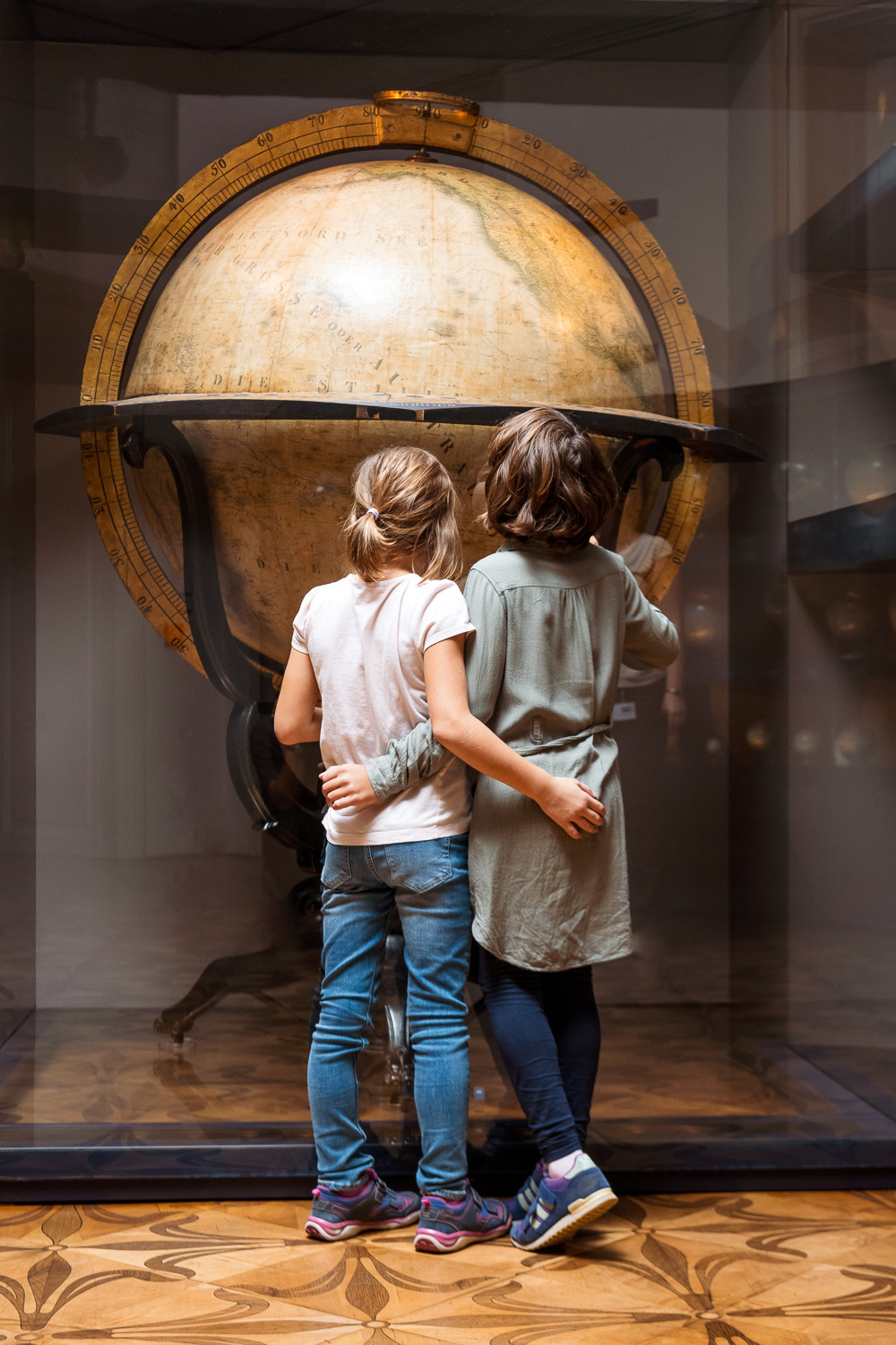 Foto von zwei Kindern, die vor einem alten Globus stehen