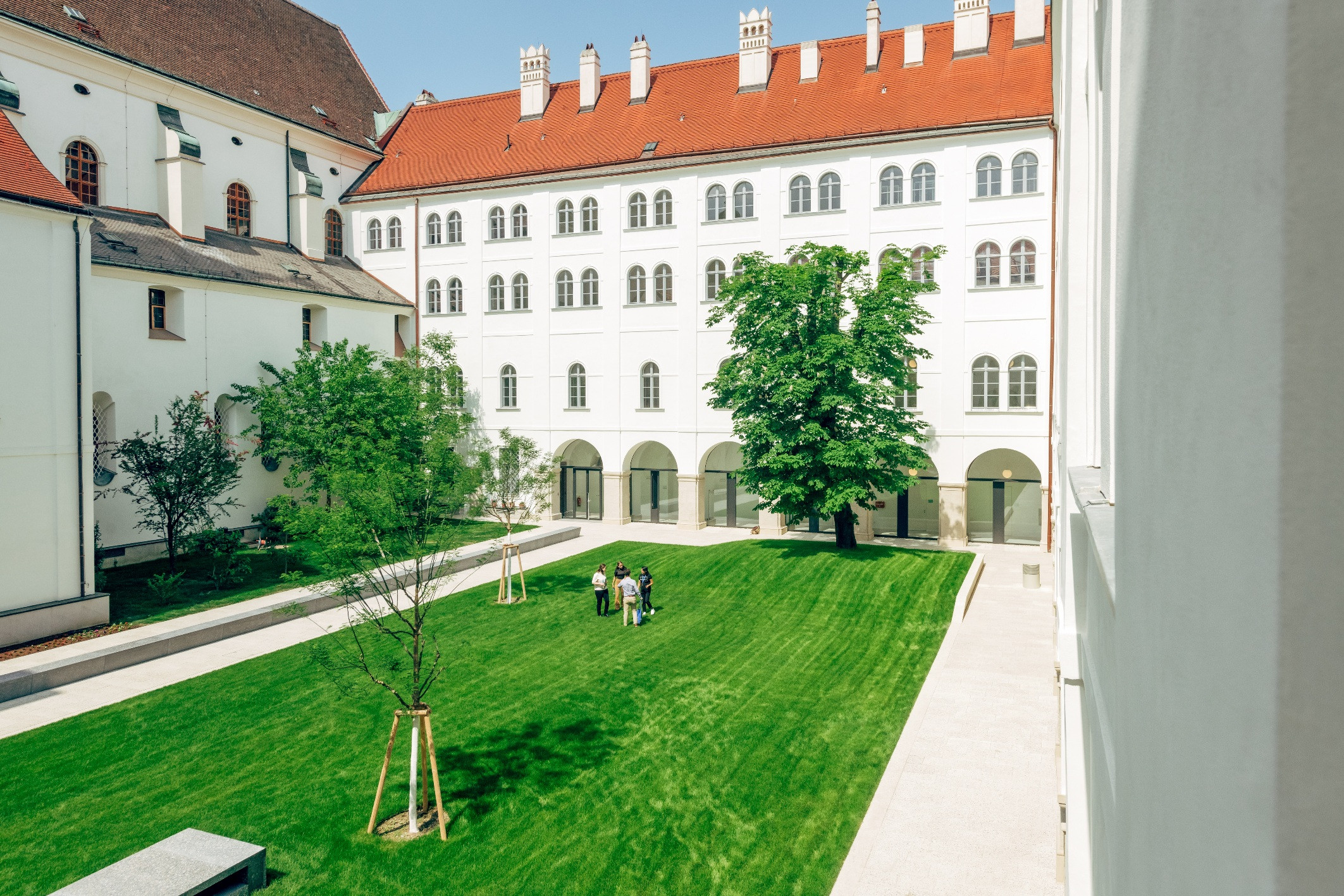 Blick auf den begrünten Innenhof mit Arkaden und der Seitenfassade der Jesuitenkirche